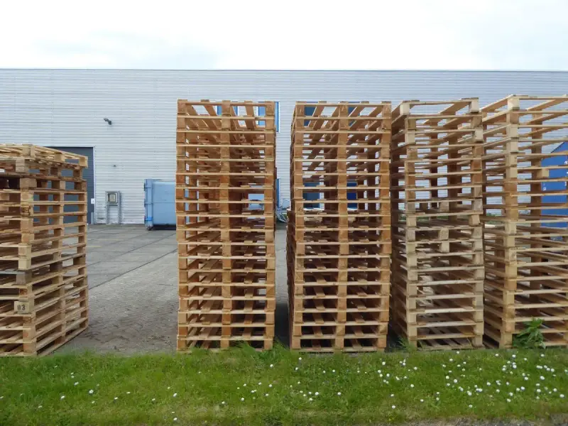 Rows of wooden pallets stacked outside an industrial warehouse