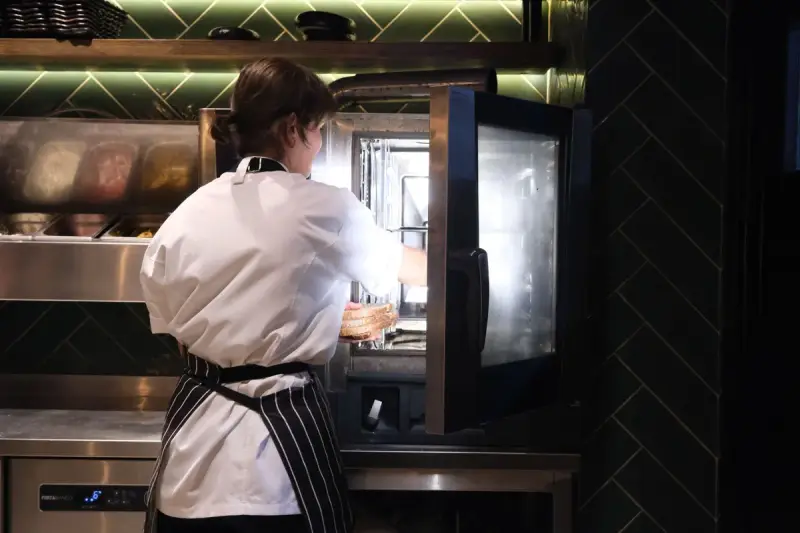 Chef in an apron preparing food at a commercial kitchen oven