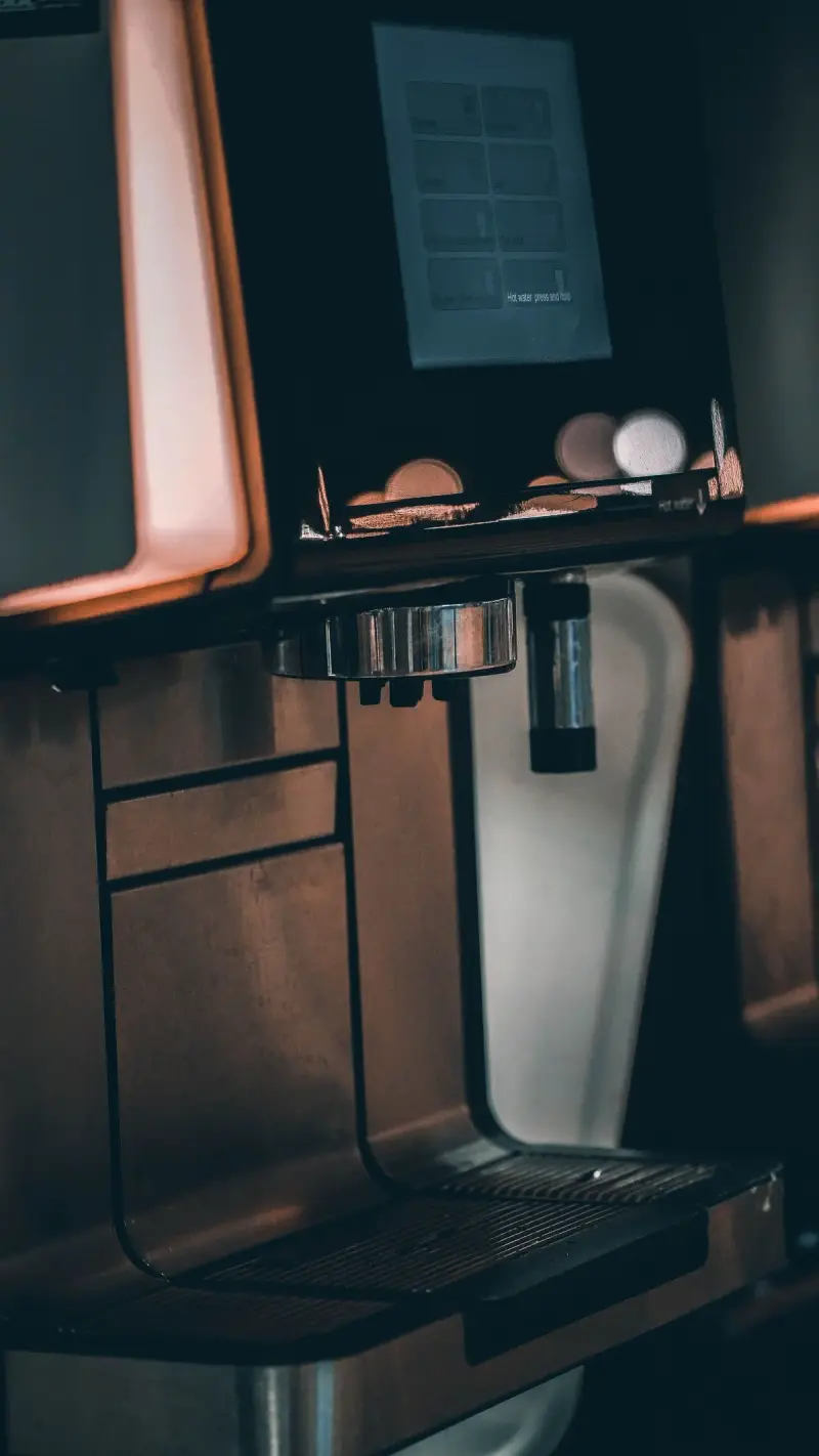 Close-up of a commercial bean-to-cup coffee machine with a touchscreen and drip tray