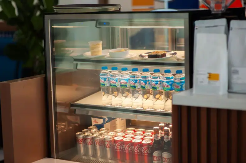 Glass refrigerated case stocked with bottled water, canned drinks and desserts