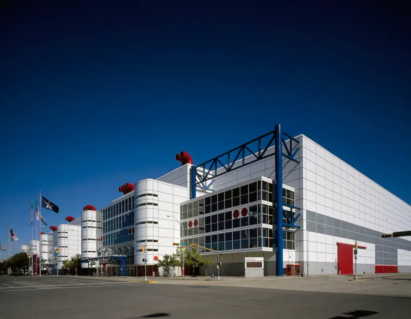 White George R. Brown Convention Center in Houston with blue steel trusses and red stacks under a deep blue sky