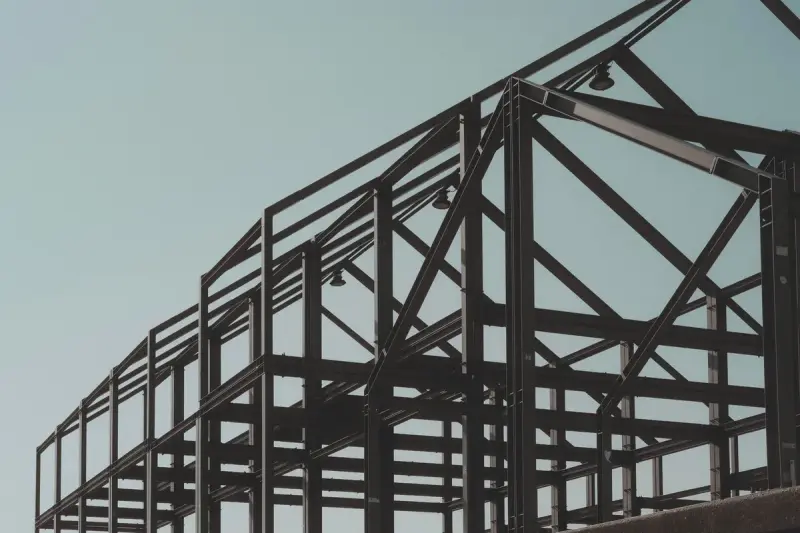 Structural steel building frame of columns and beams against a clear blue sky