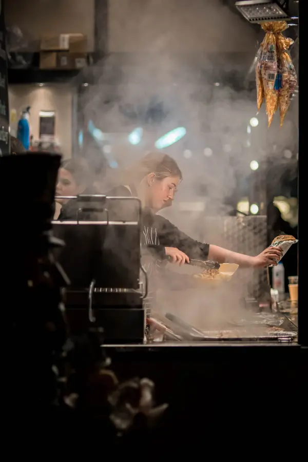 Female chef cooking at a steaming restaurant kitchen station