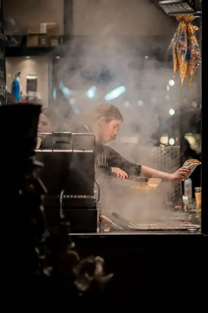 Female chef cooking at a steaming restaurant kitchen station