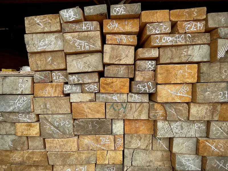 Stacked wooden planks with numbers written on their ends in a warehouse
