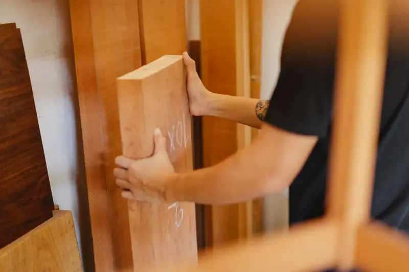 Man choosing a plank from a pile of timber in a wood store