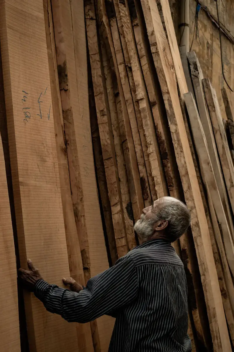 Senior woodworker inspecting stacked wood in a workshop