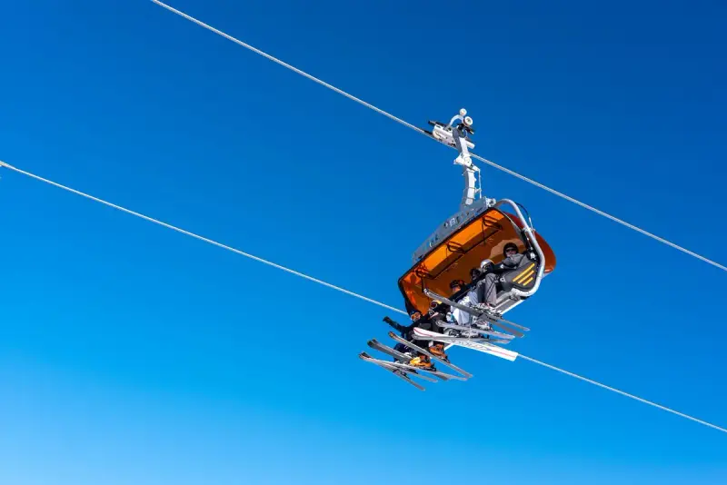 Orange chairlift with skis dangling against a deep blue sky