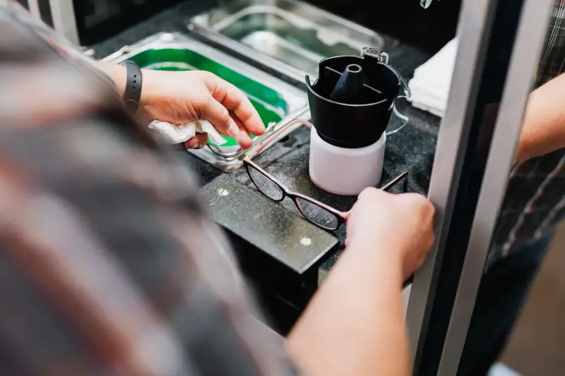 Optician cleaning eyeglasses at an optical workstation