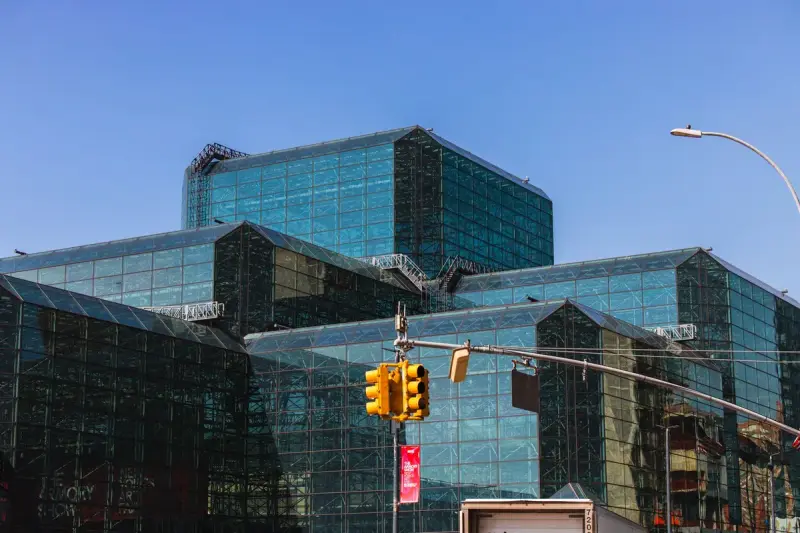 Stepped glass and steel facade of the Javits Center against a clear blue sky
