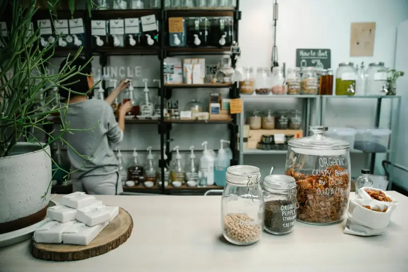 Organic food store counter with glass jars of chickpeas and banana chips, soap bars and refill shelves