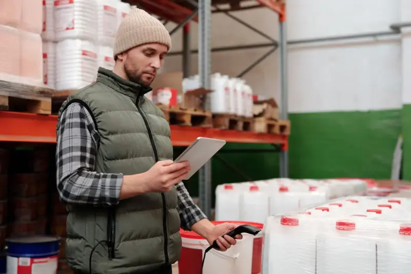 Storeroom manager scanning stock on shelves of supplies with a tablet