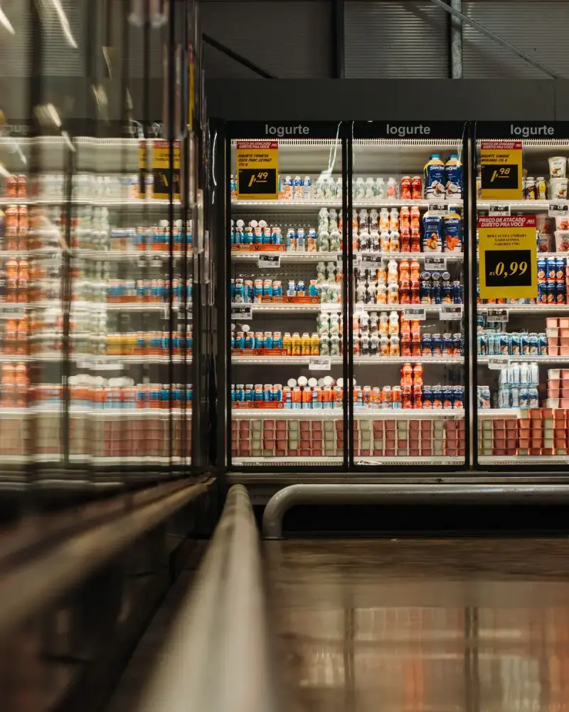 Refrigerated supermarket cases stocked with yogurt and dairy drinks beside a polished aisle