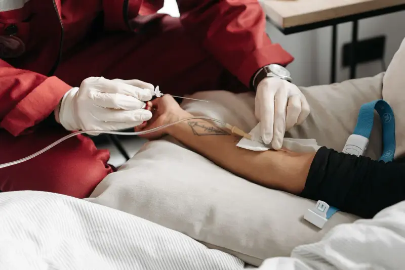 Clinician in gloves securing an IV line on a patient's arm at home
