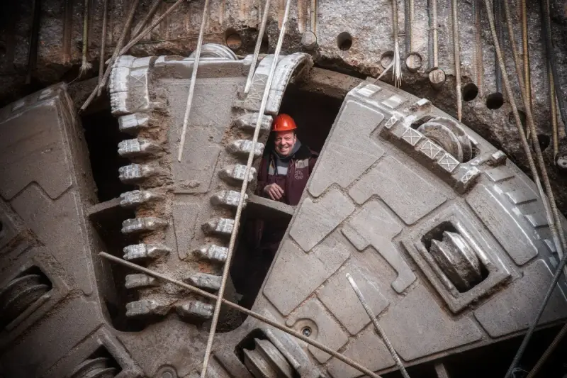 Worker in a hard hat looking out from the cutter head of a tunnel boring machine