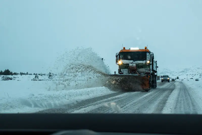 Snow plow truck throwing snow off a winter highway