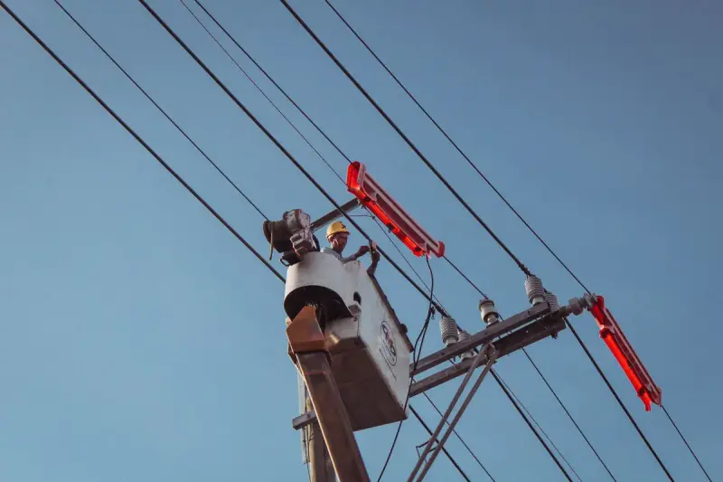 Electrician in a bucket lift repairing overhead power lines