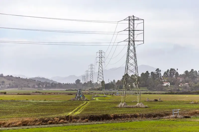 Transmission towers stretching across a rural farm field