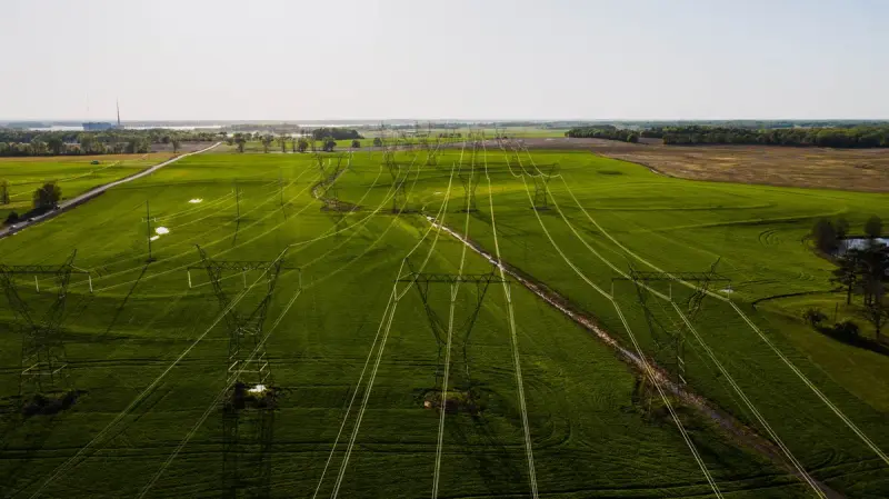 Wide green fields with electric power lines running to the horizon