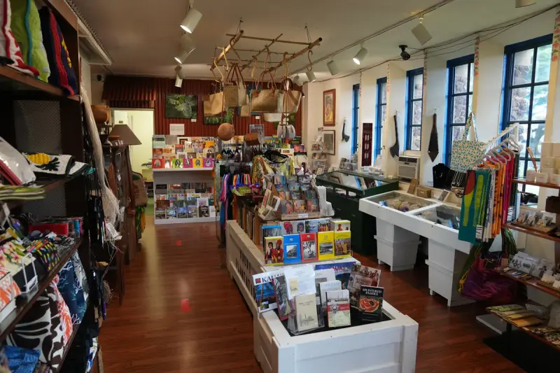 Museum gift shop with woven bags, textiles, books and cards on shelves and display tables