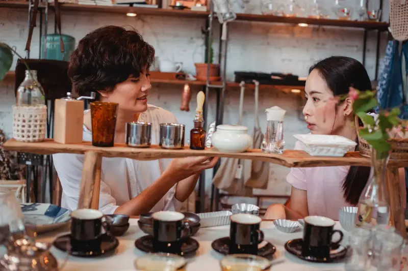 Two women talking while choosing kitchenware and ceramics in a store