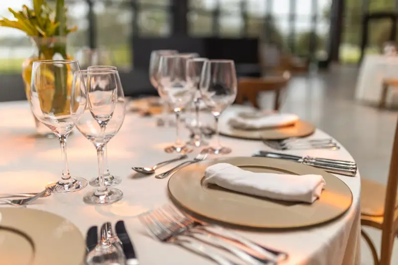 Fine dining table laid with stemware, white plates and folded napkins