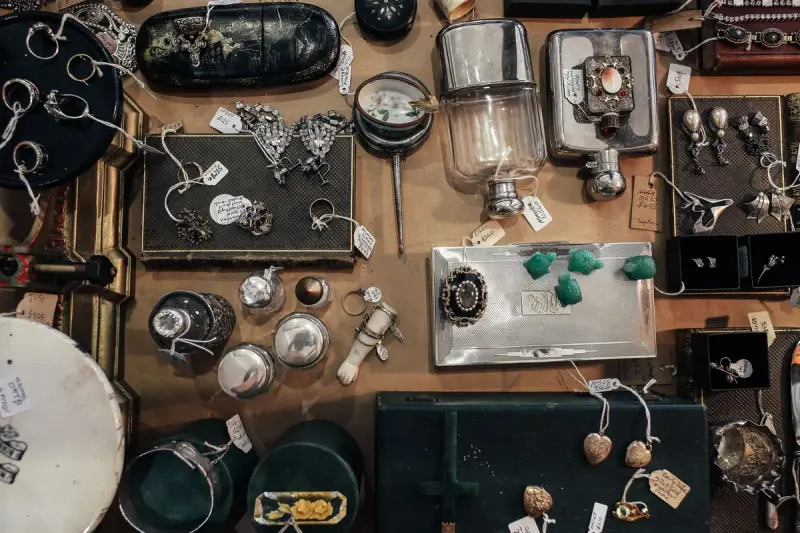 Overhead view of a dealer table of vintage jewelry, silver boxes and antiques