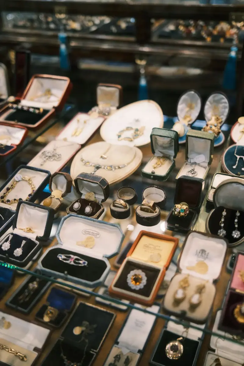 Glass case of antique rings, brooches and earrings in vintage jewelry boxes