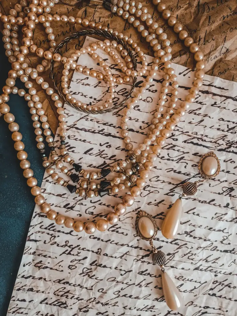 Vintage pearl necklaces and drop earrings laid over a handwritten letter