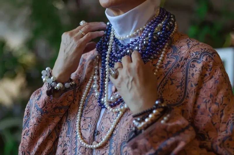 Senior woman wearing several strands of pearls and beaded necklaces