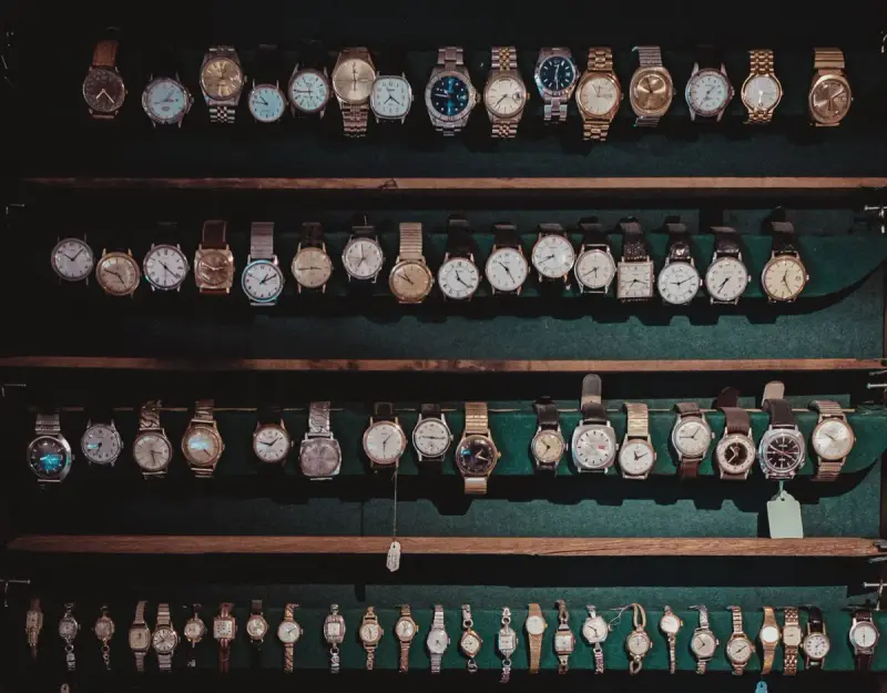Collection of vintage wristwatches lined on dark wooden shelves