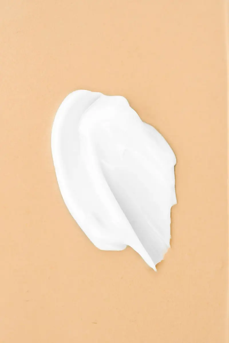 Swirl of white face cream texture on a peach background