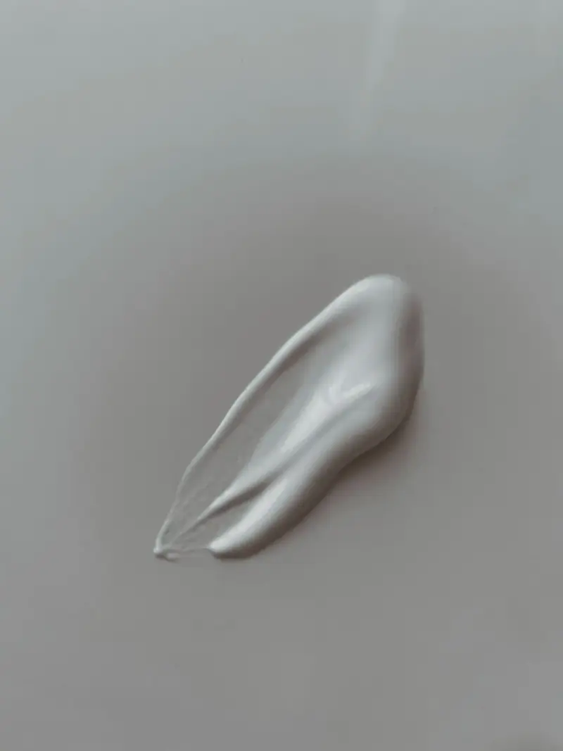 Smear of pearly silver cream texture on a gray surface