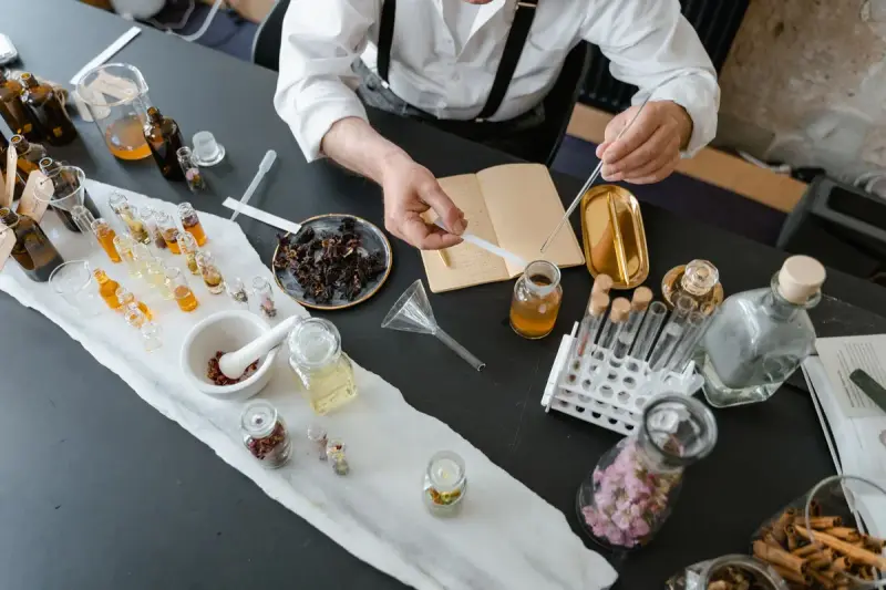 Overhead view of a fragrance workbench with vials, botanicals, funnels and glassware