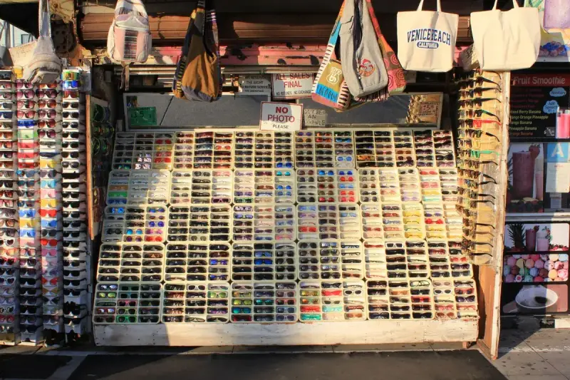 Rows of sunglasses in many styles on a sunny beach market stand