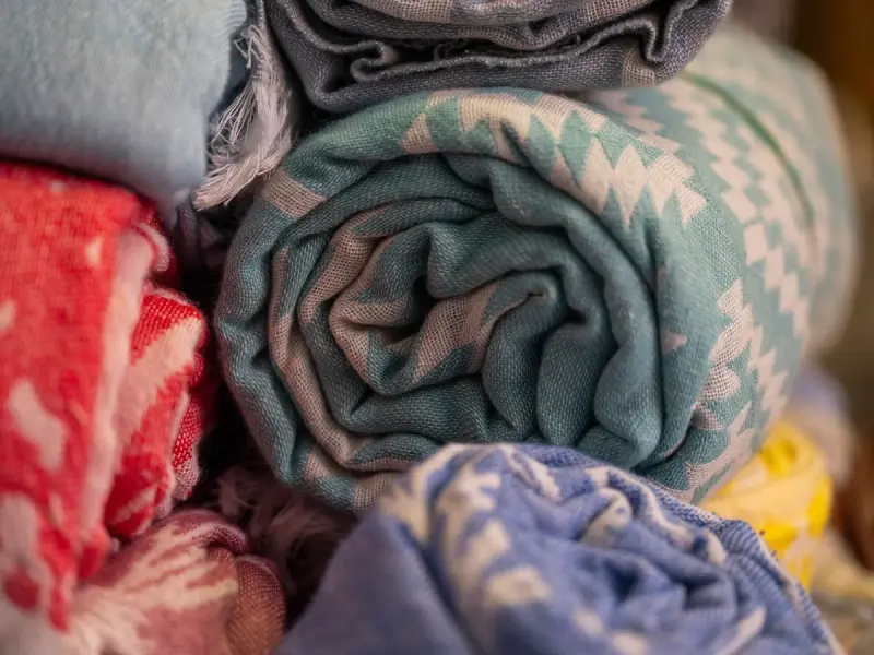 Close-up of brightly patterned rolled towels stacked on a market display