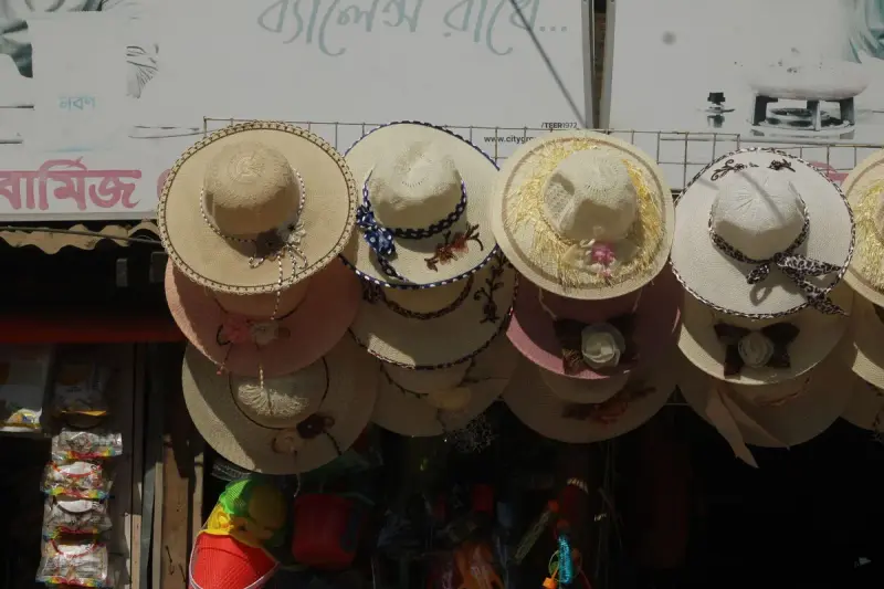 Rows of decorative straw hats hanging at an outdoor market