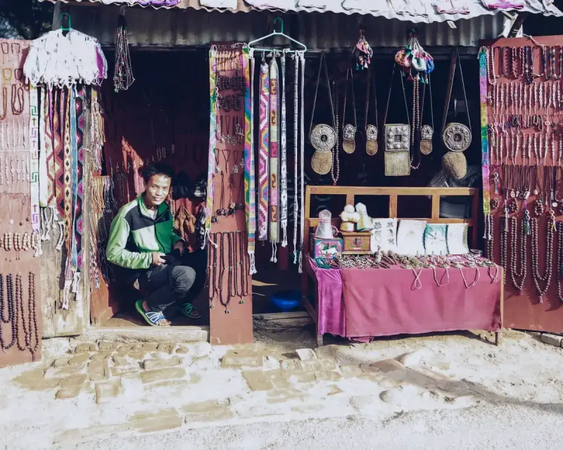 Shop owner crouching among handmade jewelry and decorative crafts in his gift store
