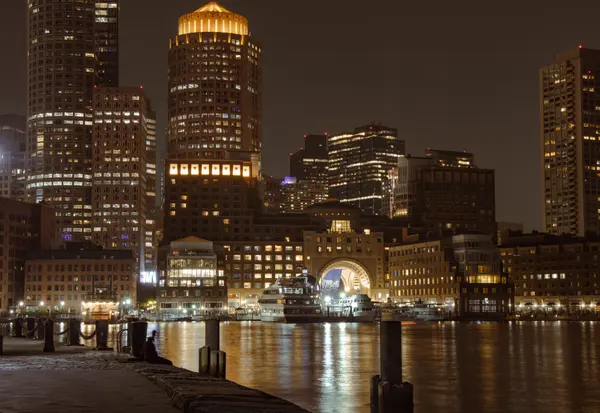 Boston waterfront towers and harbor lit at night, seen from Fan Pier Park