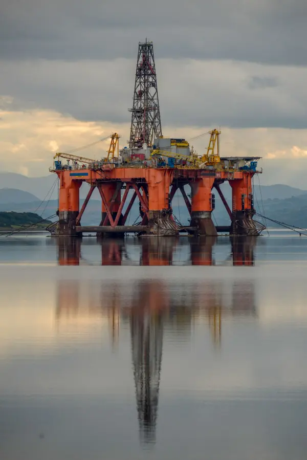 Offshore drilling platform reflected in calm water beneath clouds