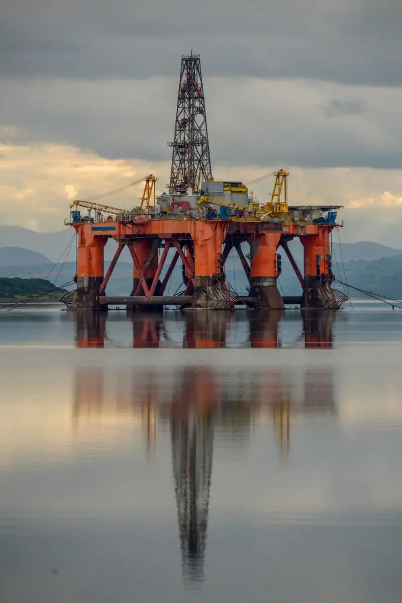 Offshore drilling platform reflected in calm water beneath clouds