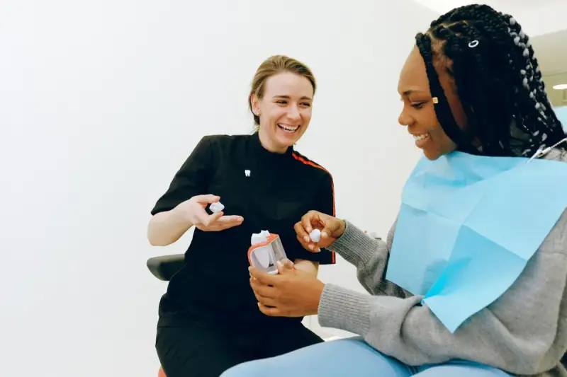Female dentist discussing a dental model with an adult patient