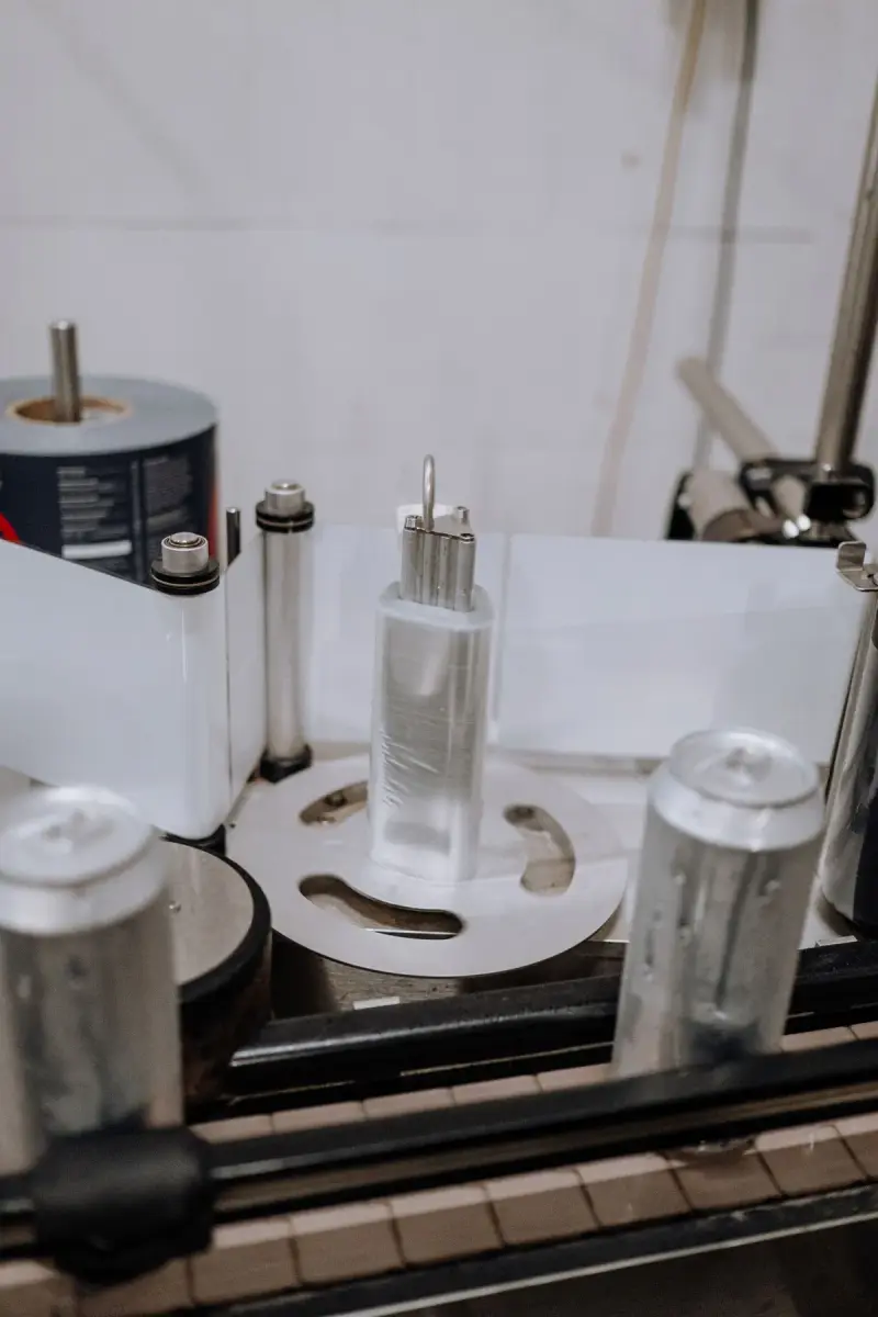 Close-up of an automated labeling machine applying labels to beverage cans