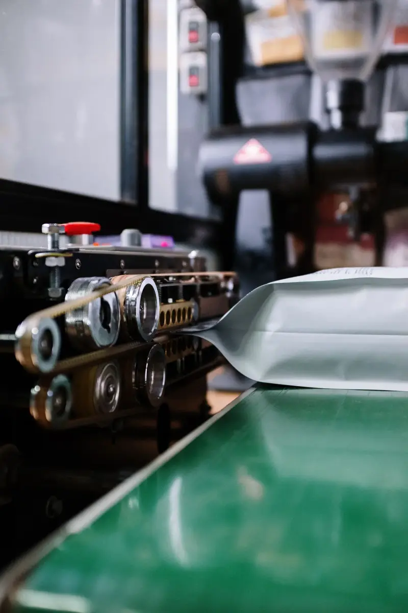 Close-up of an industrial heat-sealing machine closing the top of a coffee bag