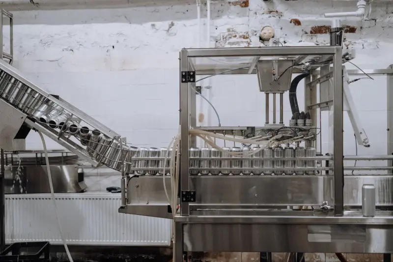 Aluminum beverage cans moving along an automated packaging conveyor in a factory
