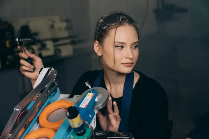 Young female engineer adjusting industrial machinery in a workshop