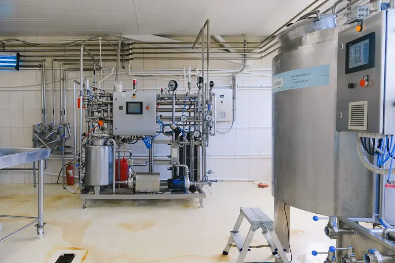 Stainless steel process skid with pipework, control panel and tanks in a bright production room