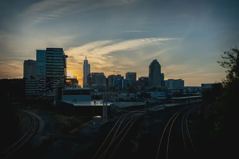 Downtown Raleigh skyline at sunset above rail tracks