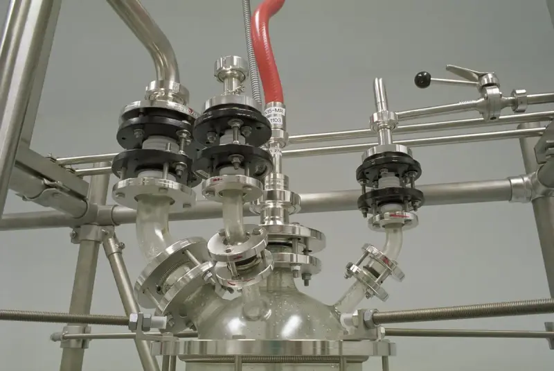 Polished stainless steel pipes, valves and a glass vessel on a production rig