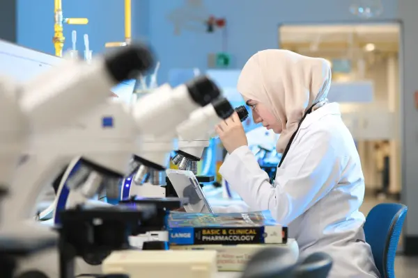 Female scientist examining samples through a laboratory microscope